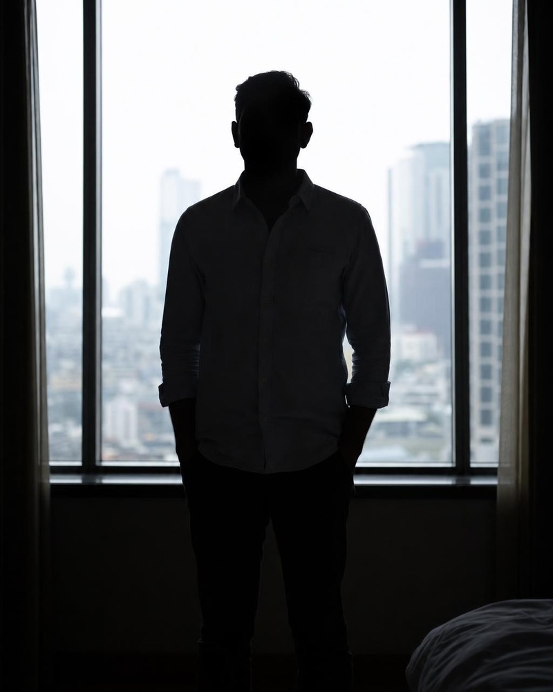 Hombre a contraluz casi en silueta frente a una ventana luminosa
